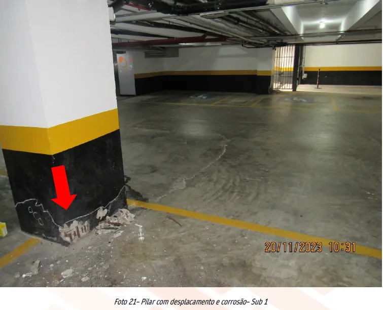 Engenheira examinando fissura em pilar durante vistoria predial para o relatório técnico conforme a ABNT NBR 16.747